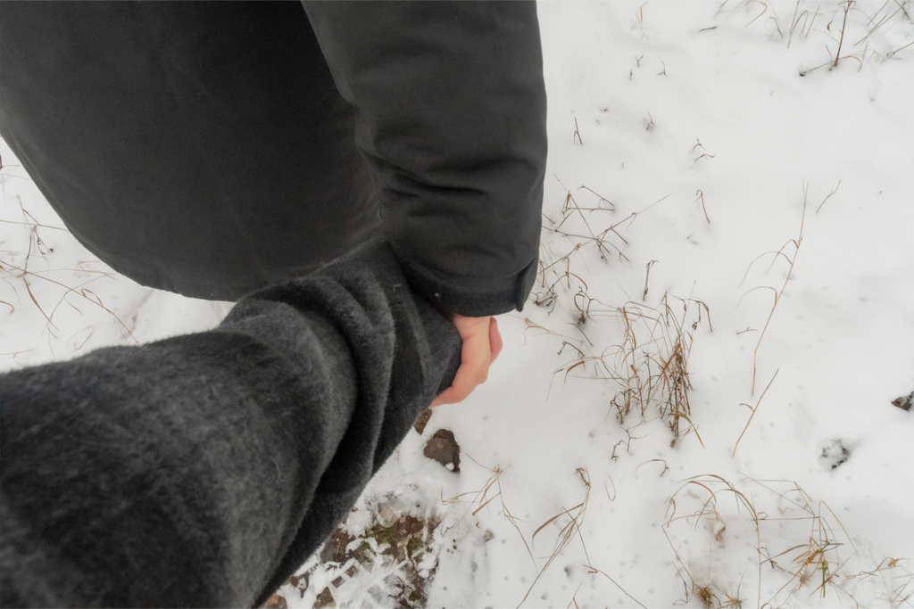 Kaksi ihmistä pitelevät toisiaan hellästi kädestä lumisessa maisemassa.