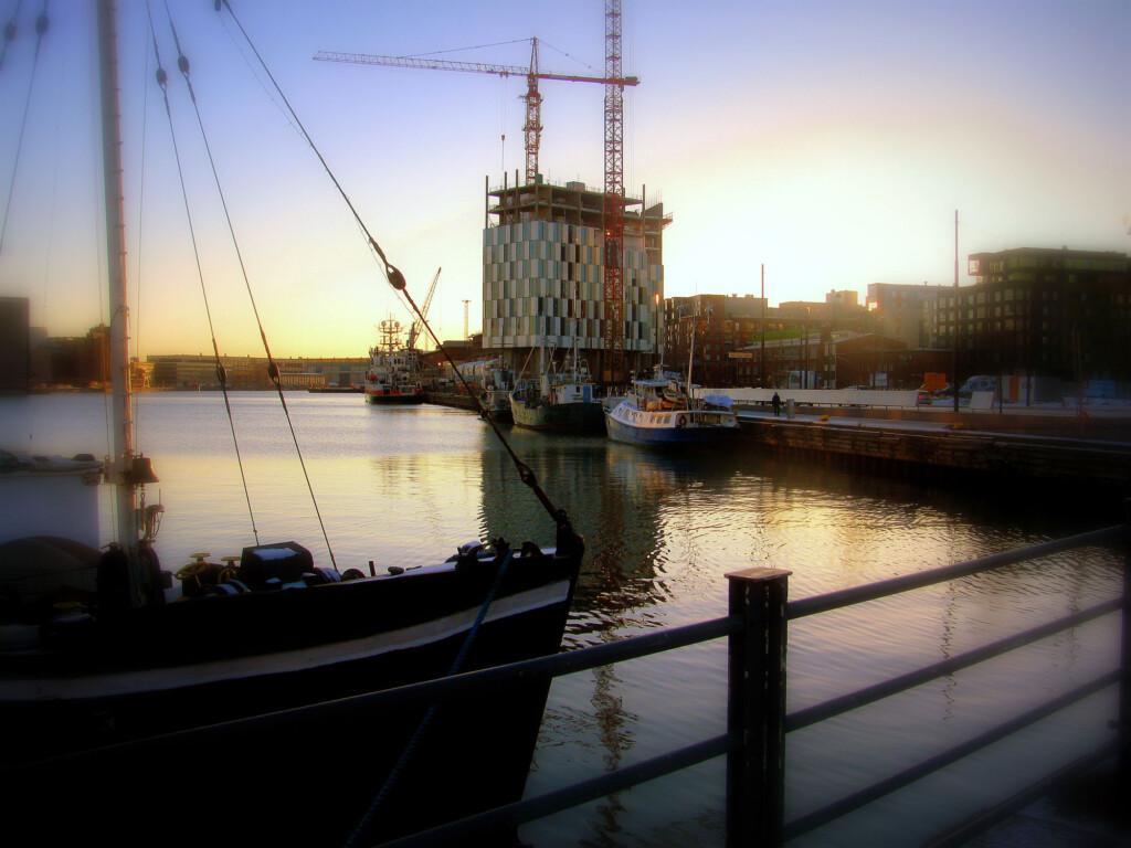 veneen keulan ohi näkyy rakennusvaiheessa oleva talo ja auringonlaskun taivasta