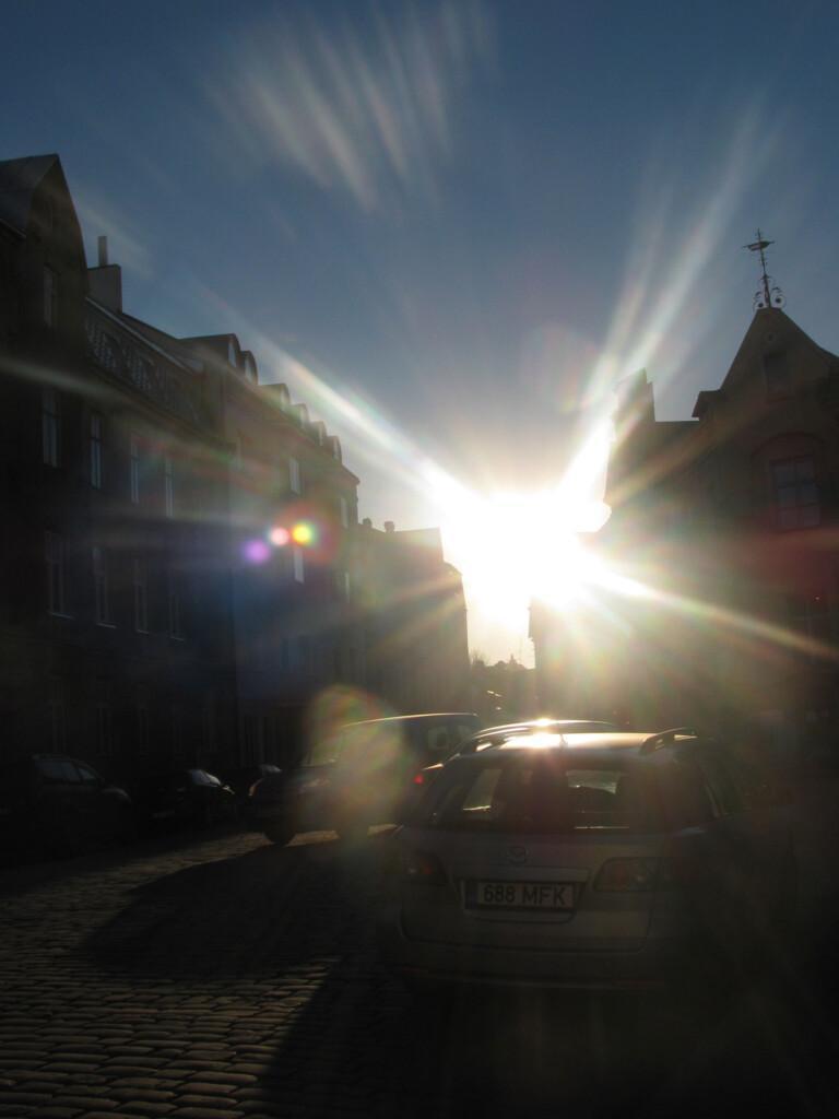 talojen siluetit piirtyvät niiden välistä siivilöityvää auringon valoa vasten